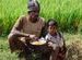 Man & child eating in rice field, road Mysore to Somnathpur - Karnataka